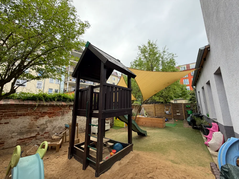 Blick in den Garten mit Spielturm, Rutsche und Sandfläche