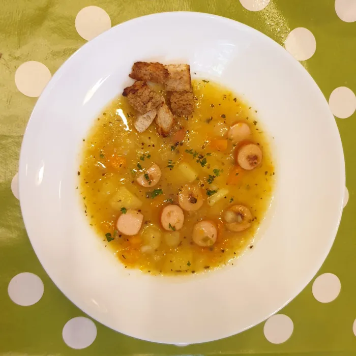 Teller mit Kartoffelsuppe und Würstchen
