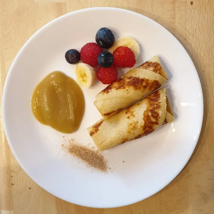 Teller mit Pfannkuchen, Apfelmus und Obst